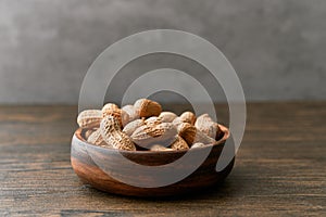 Image of bunch of peanuts in a bowl on a wooden table