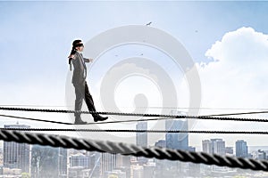 Image of businessman balancing on rope. Risk concept