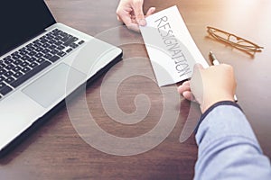 Image of businessman hand sending a resignation letter to executive boss with glasses, pen and laptop on a wooden table, Change