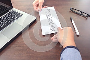 Image of businessman hand sending a resignation letter to executive boss with glasses, pen and laptop on a wooden table, Change