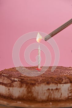 Image of a candle lighting up on a cake decorated with chocolate, copy space