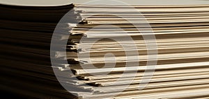 A close up view of a large stack of old yellowed paper documents and books