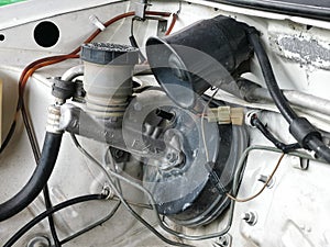 Image of car break pump system and horn speaker mount on car engine bay.