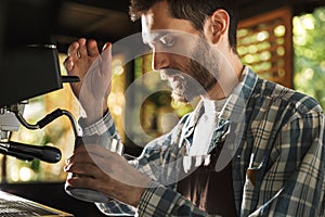 Image of caucasian barista boy making coffee while working in cafe or coffeehouse outdoor