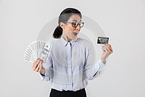 Image of caucasian office woman wearing eyeglasses holding bunch of money and credit card, isolated over white background