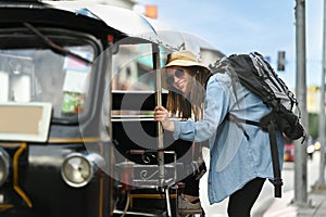 Image of caucasian woman tourist getting in local Tuk Tuk taxi for exploring the city in Thailand