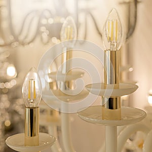 Image of a chandelier with white glass fittings and candlelight shades on a gold stand