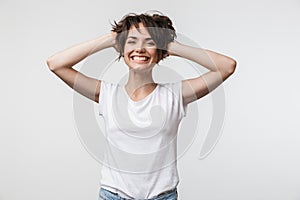 Image of charming woman with short hair in basic t-shirt laughing and grabbing her head