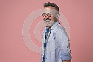 Image of cheerful excited handsome mature businessman standing isolated over pink background. Looking camera.