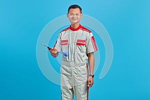 Image of cheerful handsome man wearing mechanical uniform holding clipboard and looking at camera