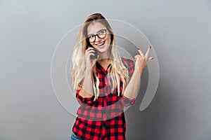 Cheerful young blonde woman talking by phone.
