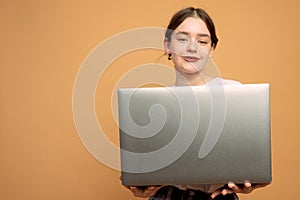 Image of cheerful young woman standing isolated over orange background using laptop computer. Looking at the camera
