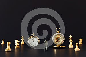 Image of chess game. Businessman looking at vintage clock, compass and pawns, competition, strategy, leadership and success