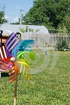 Image of childish colorful pinwheel on the outside. Garden with green grass in a sunny summer day. Rainbow flag LGBT Happy colors