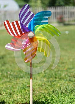 Image of childish colorful pinwheel on the outside. Garden with green grass in a sunny summer day. Rainbow flag LGBT Happy colors photo