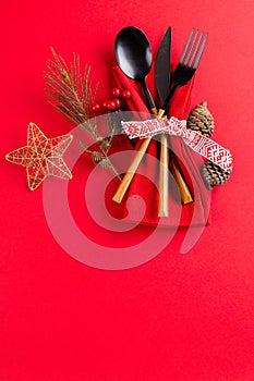 Image of christmas place setting with cutlery, christmas decoration and copy space on red background