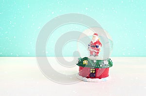 Image of christmas snow glass ball with santa claus in front of pastel blue background