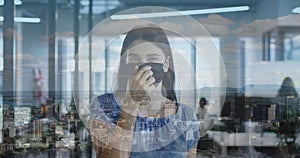 Image of cityscape over caucasian woman wearing face mask in office
