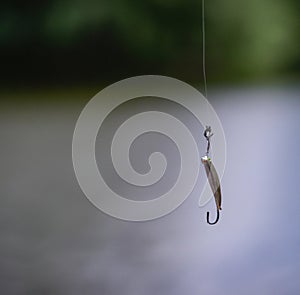 Image of close up of fishing line with bate against out of focus water