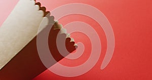 Image of close up of white popcorn tub with copy space on red background
