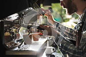 Image closeup of attractive barista man making coffee while working in cafe or coffeehouse outdoor