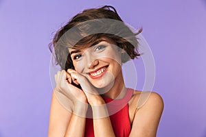 Image closeup of caucasian satisfied girl 20s in casual wear smiling and holding hands at face, isolated over violet background