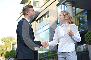 Image of collegues discussing documents and shaking hands near office