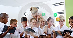 Image of colorful icons over diverse schoolchildren and teacher using tablets