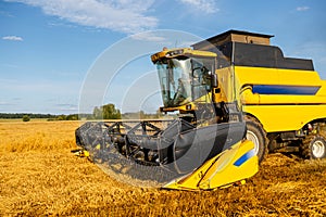 Image of combine harvesting wheat, blue sky.