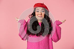 Image of confused beautiful asian girl wearing beret throwing up arms