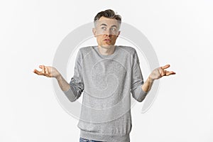 Image of confused middle-aged man with grey hair, shrugging and looking away, cannot understand something, standing over