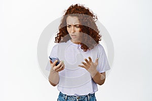 Image of confused redhead woman cant understand how to use application, bad user experience with smartphone app, looking photo