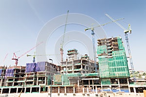 Image of construction site against blue sky with multiple tower cranes