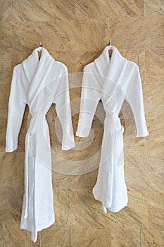 The image of couple white bathrobes on a hanger in bathroom.