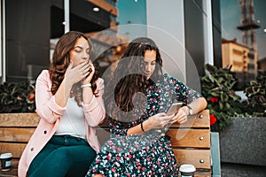 Image of curious woman spying and peeping at smartphone of her friend, while talking on mobile phone