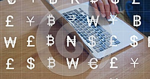 Image of currency symbols over hands using laptop