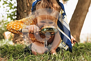 Image of cute kid with magnifying glass exploring the nature outdoors. Adorable little girl playing in the forest with magnifying