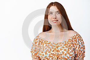 Image of cute redhead girl yearning to try something, looking aside and thinking, smiling pleased, biting lip thoughtful