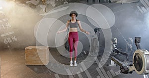 Image of data on interface over african american woman jumping rope, cross training at gym