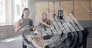 Image of data on interface over caucasian women training on rowing machines at gym