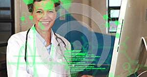 Image of data processing over happy caucasian female doctor using computer at hospital