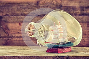 Image of decorative boat in the bottle on wooden table. nautical concept. retro filtered image