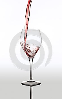 Image of delicious red wine pouring into glass isolated over gray background