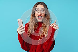 Image of delighted woman using cellphone and pointing finger upward
