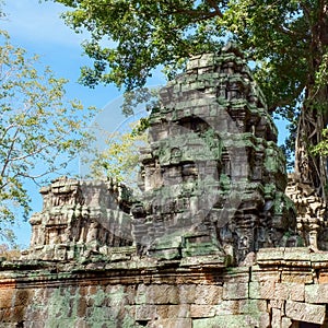 Image depicts a destroyed medieval Khmer building in Cambodia, visible amongst overgrown vegetation
