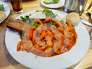 Image of a deviled shrimp dish accompanied with salad and bread