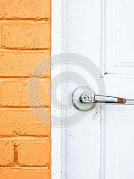 Image of dirty white wooden door with knob and yellow bricks wall.