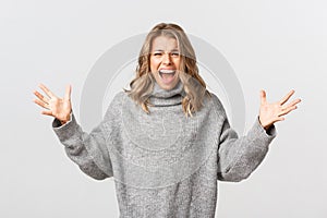 Image of distressed young woman screaming and shaking hands, standing emotional against white background