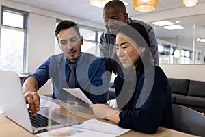 Image of diverse female and male businesspeople working on laptop in office