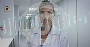 Image of dna chain over happy caucasian female doctor looking at camera